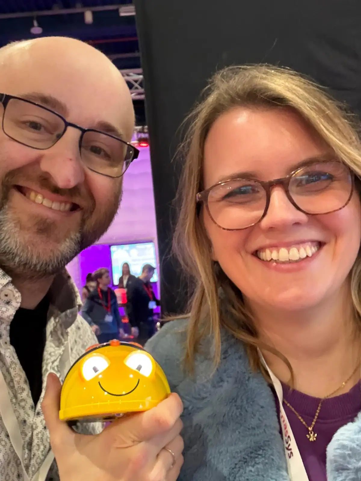 Man en vrouw lachen samen en houden een gele Bee Bot vast
